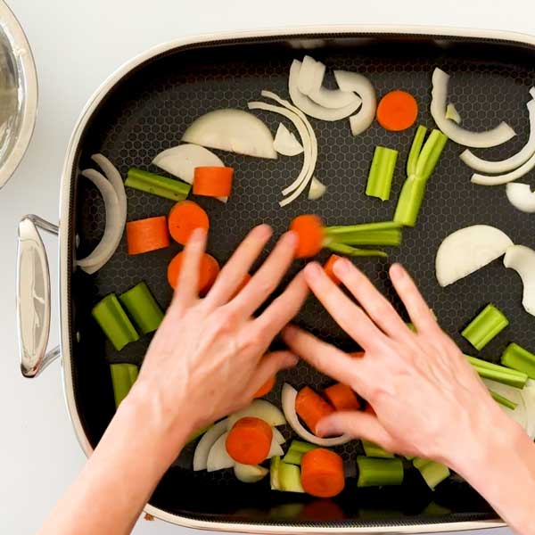 Spreading the vegetables in the bottom of the roasting pan.