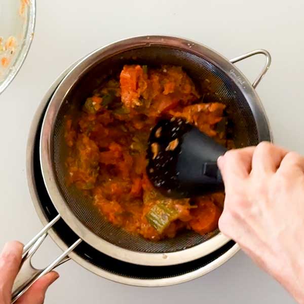 Straining the vegetables into the gravy.