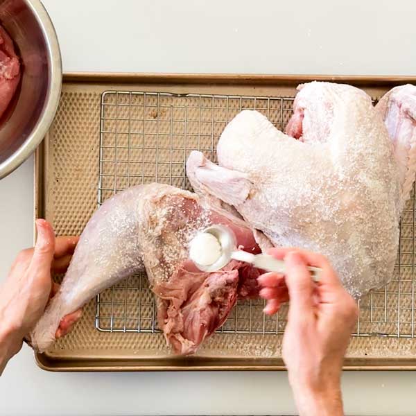 Spreading the kosher salt and baking powder mix over the turkey skin.