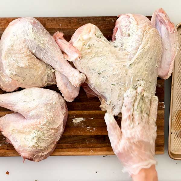 Spreading garlic butter under and on top of the skin.