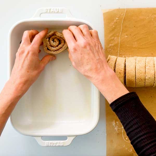 Placing the sliced cinnamon rolls in a baking dish.