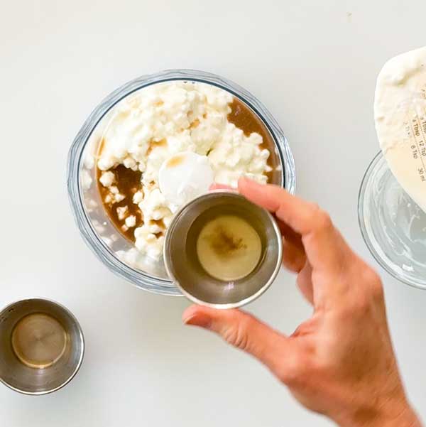 Adding the wet ingredients to the cottage cheese in a blender cup.