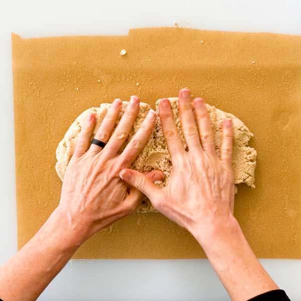Spreading the cinnamon roll dough on a parchment paper sprayed with coconut oil.