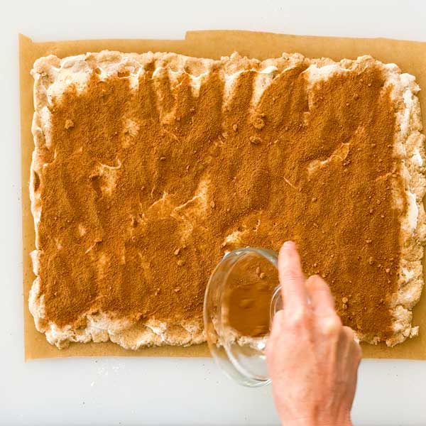 Sprinkling the coconut sugar and cinnamon mixture over the butter layer.