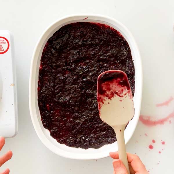 Spreading the cherry compote in a shallow dish to cool quickly.