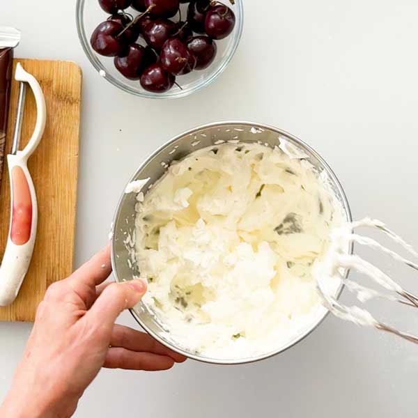 The whipped cream with stiff peaks in a bowl.
