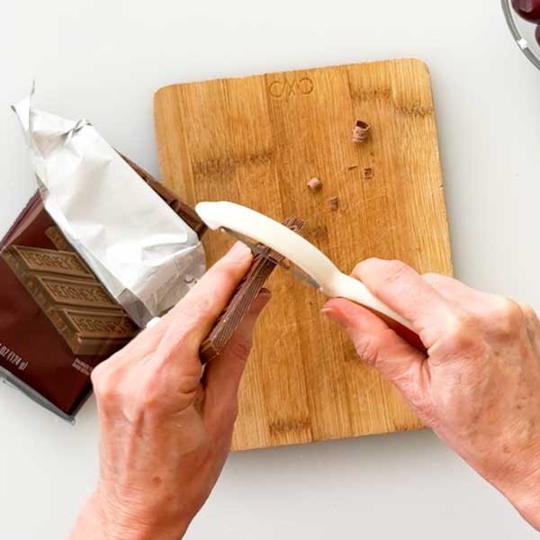 Shaving chocolate curls with a vegetable peeler off a chocolate bar.