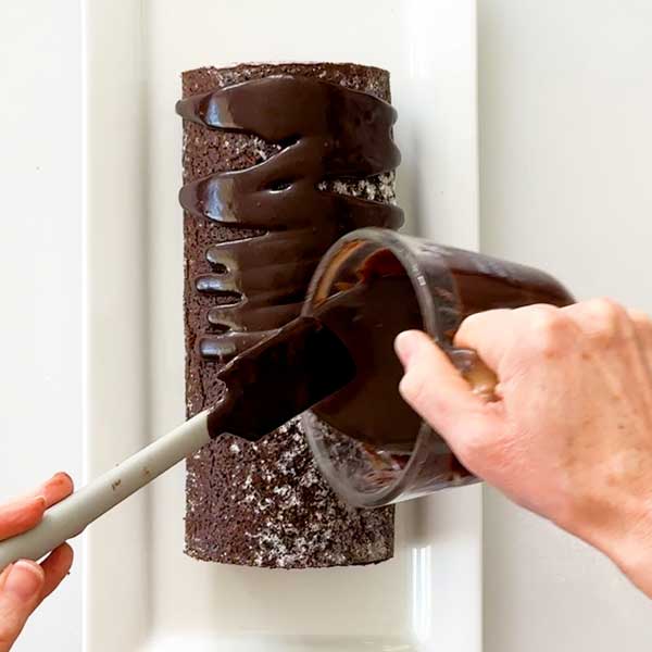 Pouring the chocolate ganache over the cooled cake.