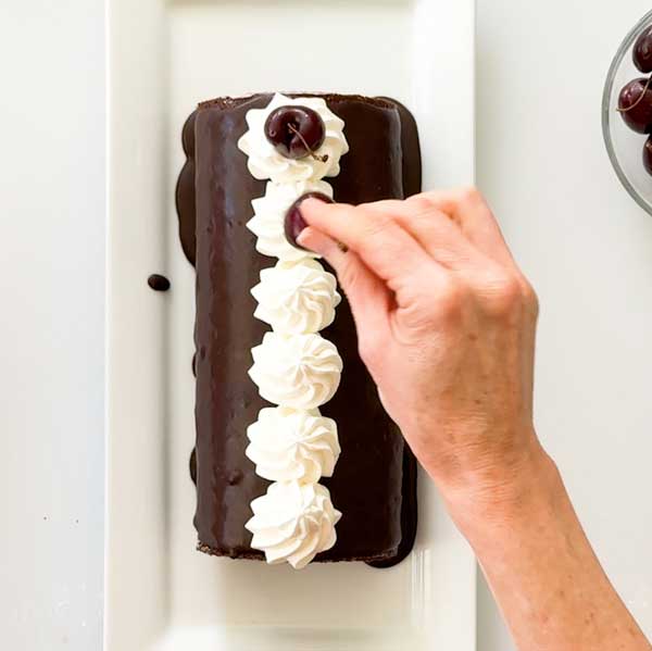Placing the cherries on top of the whipped cream dollops.