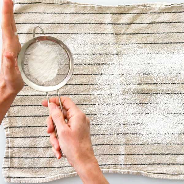 Dusting a kitchen towel with powdered sugar.