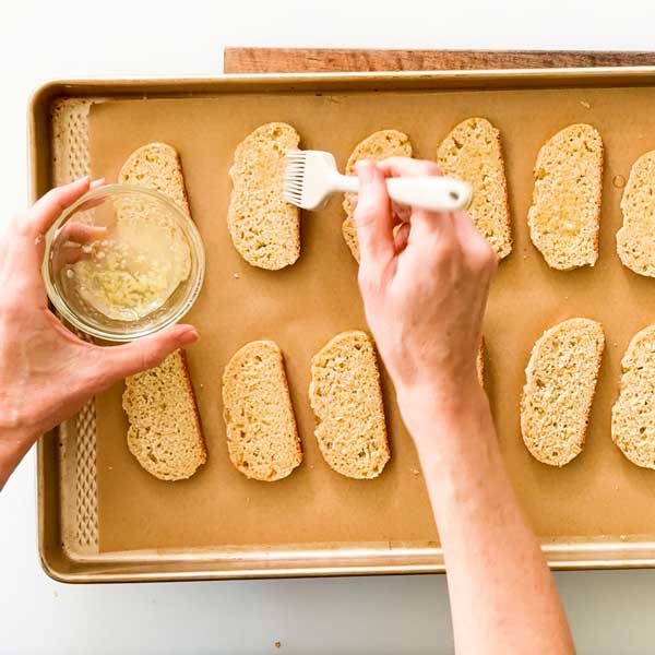 Spreading the garlic and light olive oil on the bread slices.