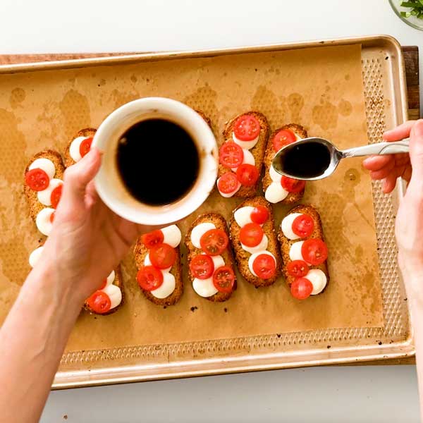 Drizzling balsamic vinegar and honey over the tomatoes.