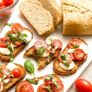 A loaf of no-yeast bread next to gluten-free crostinis with tomato, basil, and mozzarella cheese.