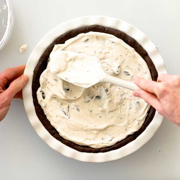 Spreading the pie filling in the cooled pie crust.
