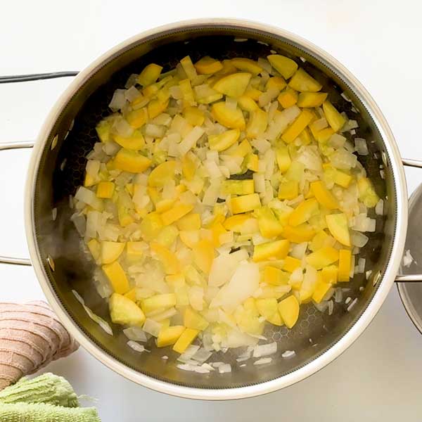 Sauteeing the onion, yellow squash and garlic in the pot.