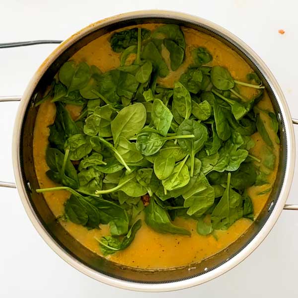 Adding the spinach leaves to the soup.