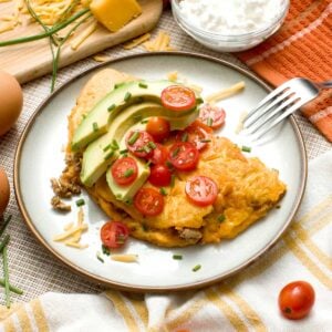 A high-protein cottage cheese omelet with tomatoes and avocado slices on top.