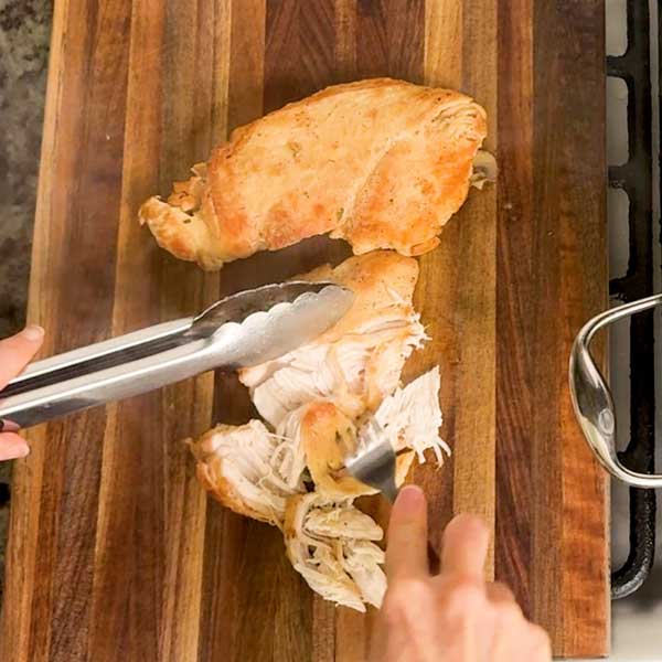 Shredding the cooked chicken with two forks.