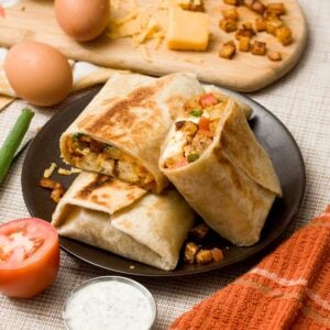 A stack of high protein breakfast burritos with crispy potatoes, ground turkey sausage, and cheese.