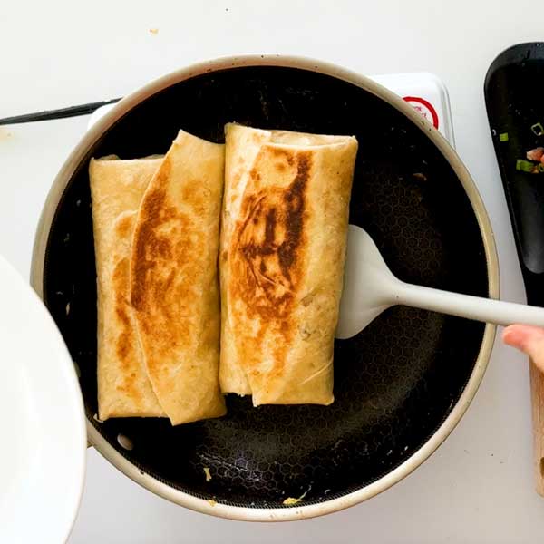 Toasting the breakfast burritos in the skillet.