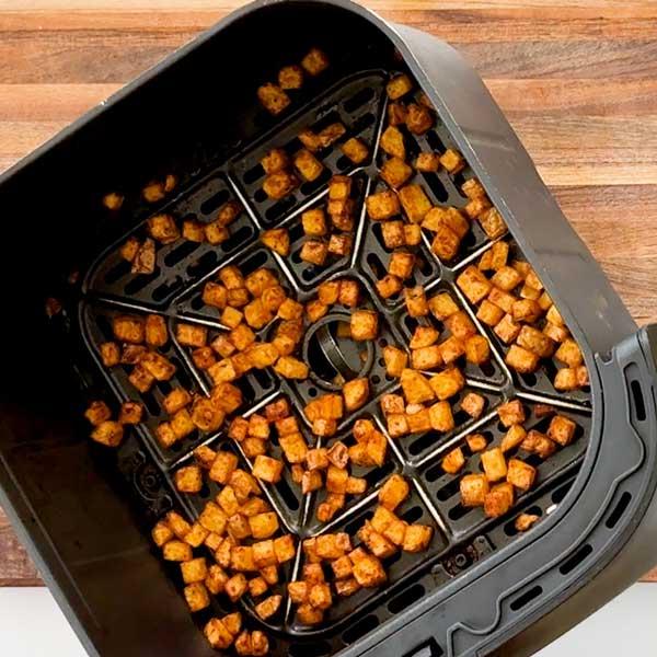 Taking the crispy potatoes out of the air fryer.