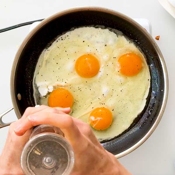 Seasoning the eggs in a skillet.